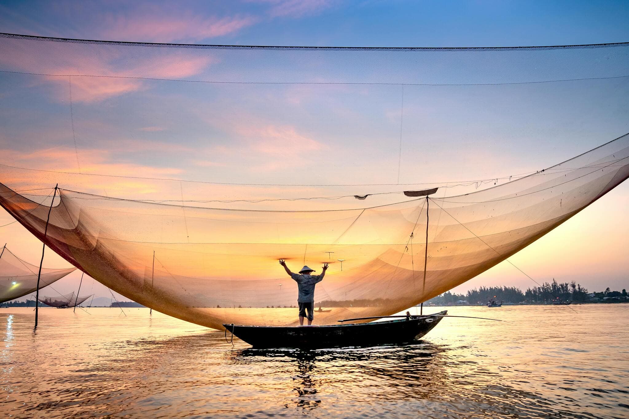 Bình minh tuyệt đẹp trên biển, với những chiếc thuyền đánh cá ở phía xa